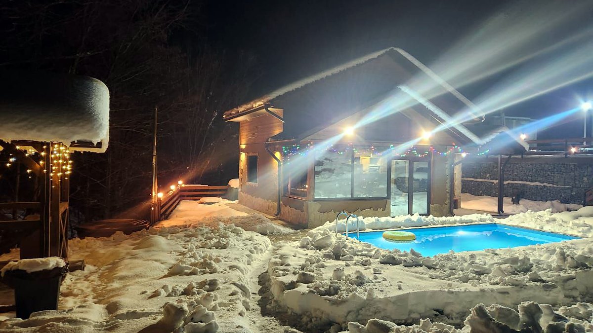 Зимняя баня на дровах с подсвеченным бассейном ночью